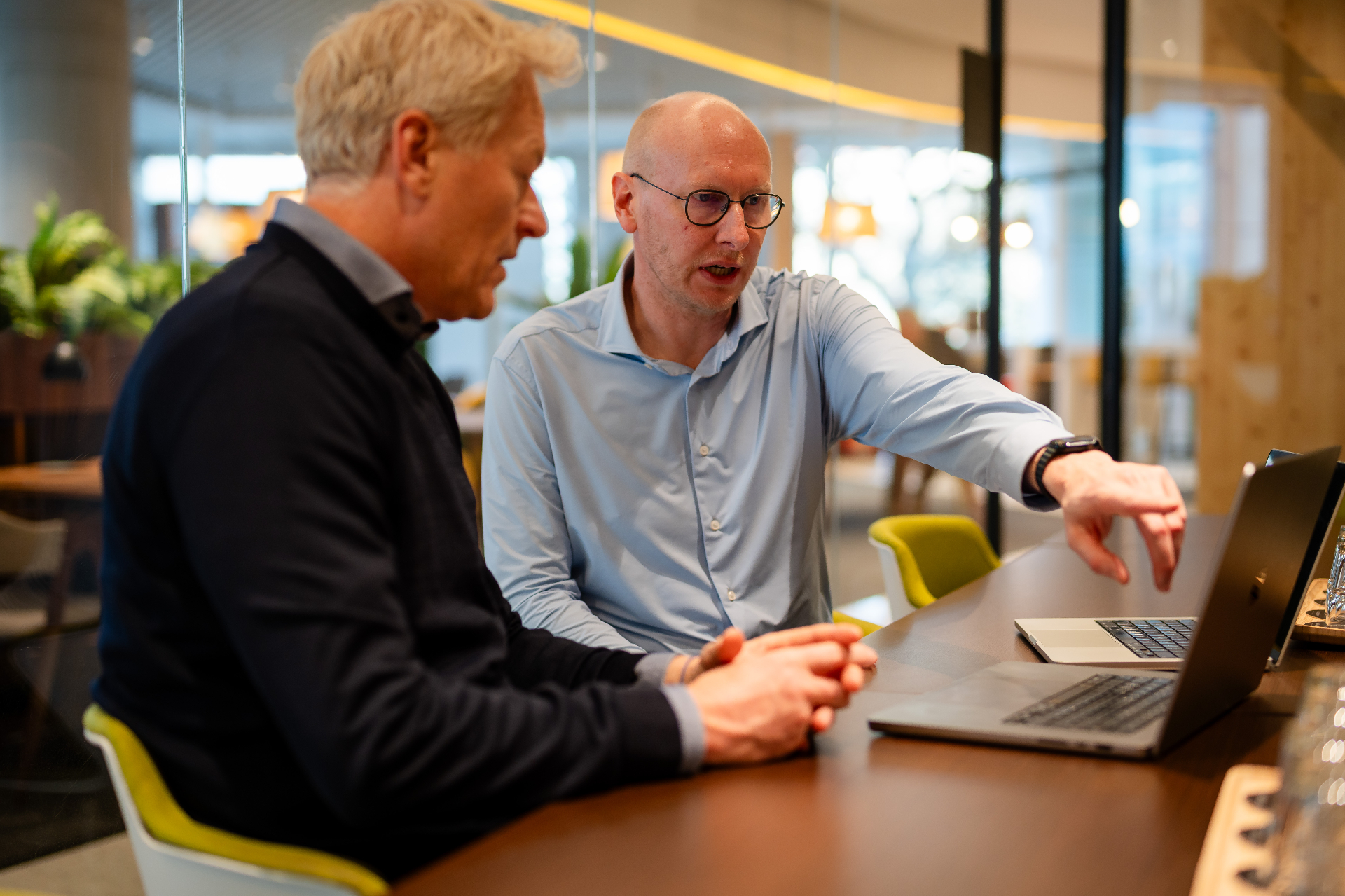 Amaii oprichters in een intensief overleg naast laptops in een moderne werkruimte