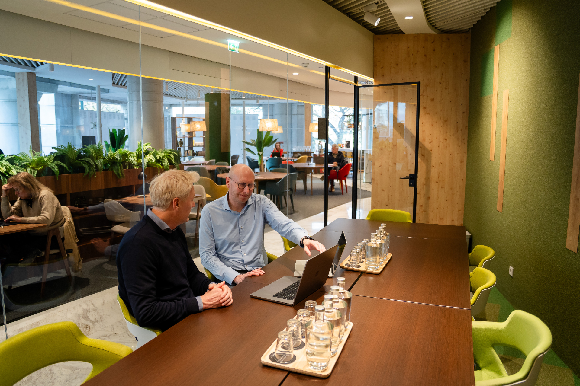 Twee Amaii oprichters aan een vergadertafel met laptop in een moderne kantooromgeving